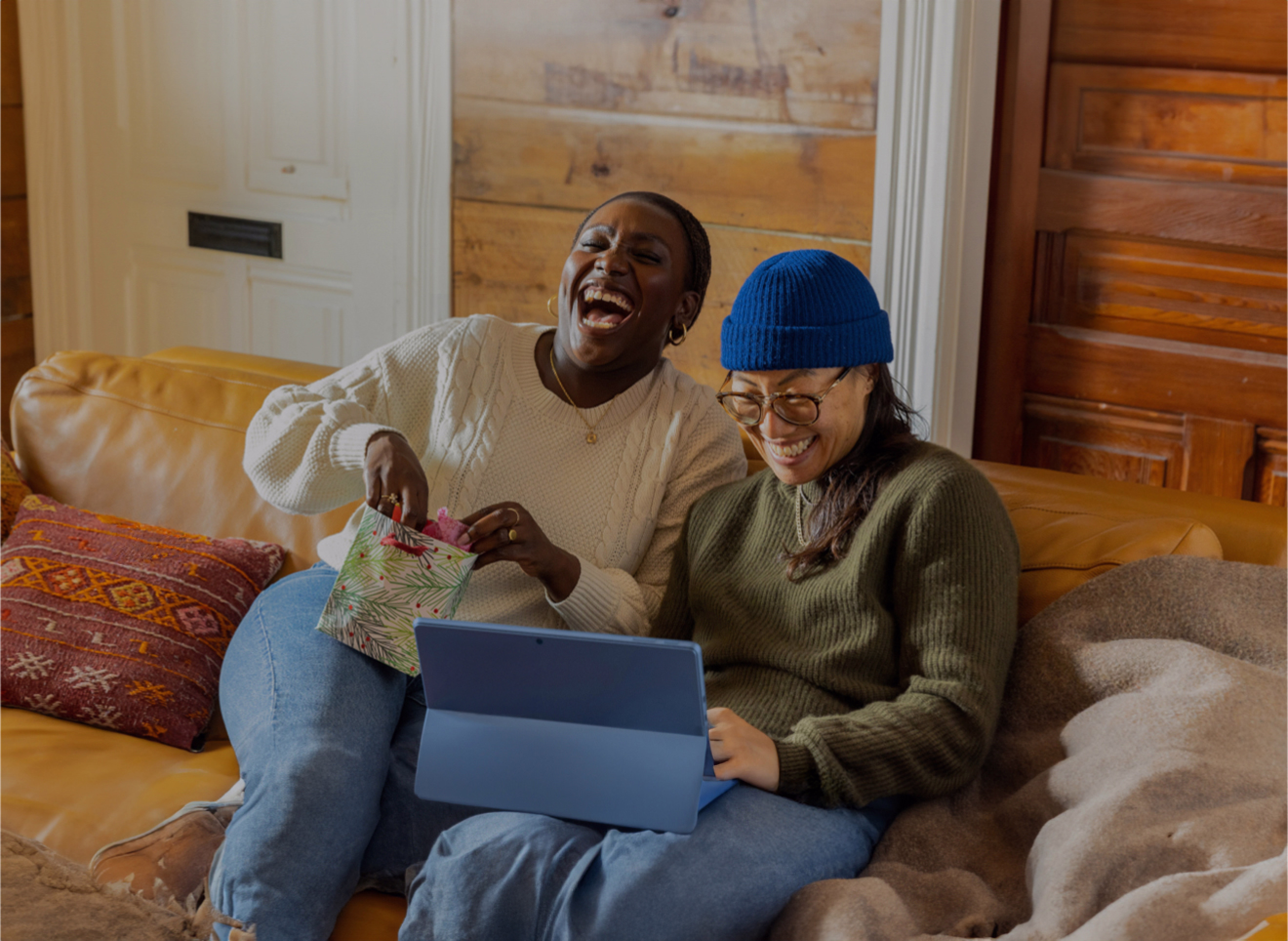 Dos mujeres con un portatil sentadas en un sofá